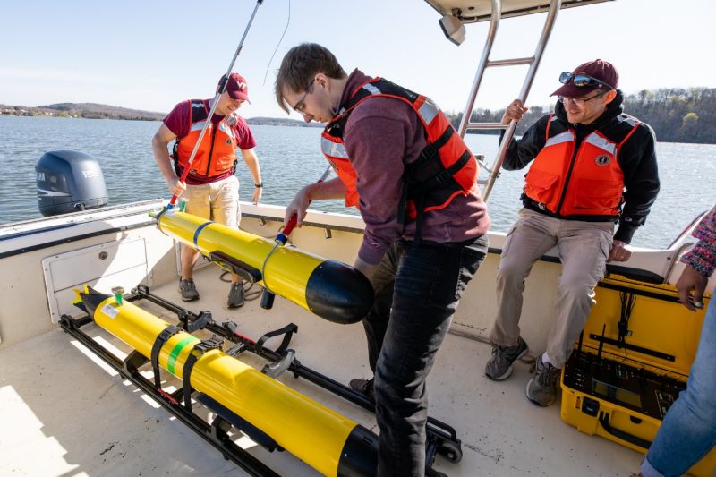 Students on a boat hoisting out subs.